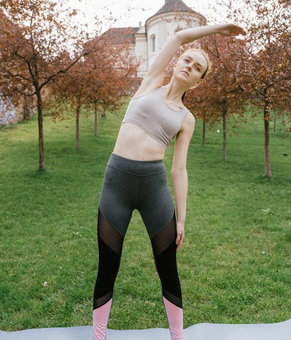 Woman in a calm yoga pose against a lilac background.